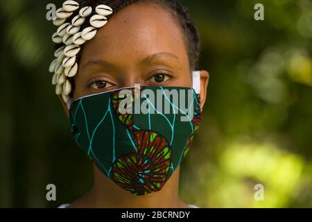 Eine kenianische Frau, die eine hausgemachte Maske trägt, aus traditionellem Kanga-Stoff zum Schutz vor einer Kovid-19-Pandemie. Chirurgische Masken befinden sich in kurzer Sup Stockfoto