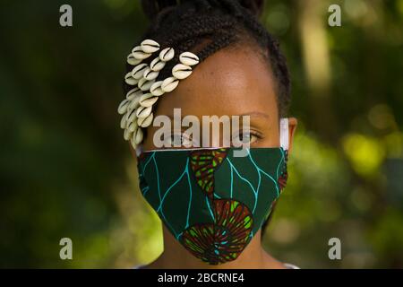 Eine kenianische Frau, die eine hausgemachte Maske trägt, aus traditionellem Kanga-Stoff zum Schutz vor einer Kovid-19-Pandemie. Chirurgische Masken befinden sich in kurzer Sup Stockfoto