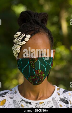 Eine kenianische Frau, die eine hausgemachte Maske trägt, aus traditionellem Kanga-Stoff zum Schutz vor einer Kovid-19-Pandemie. Chirurgische Masken befinden sich in kurzer Sup Stockfoto