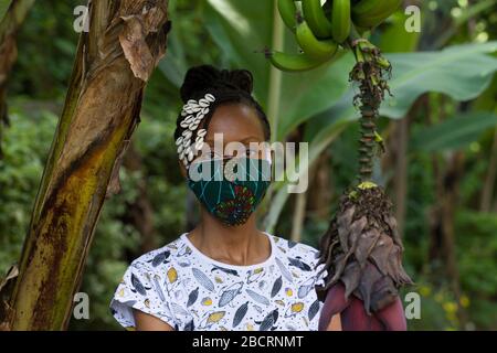 Eine kenianische Frau, die eine hausgemachte Maske trägt, aus traditionellem Kanga-Stoff zum Schutz vor einer Kovid-19-Pandemie. Chirurgische Masken befinden sich in kurzer Sup Stockfoto