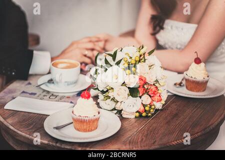Liebevolles Paar trinkt nach der Hochzeit Kaffee. Die Hände sind frisch vermählt. Stockfoto