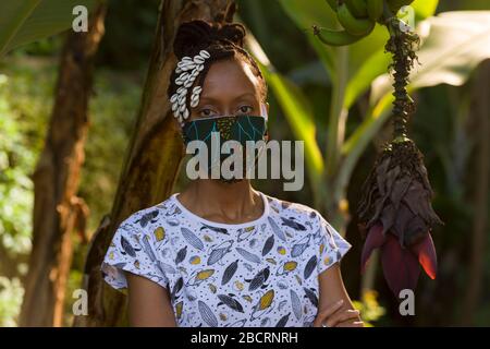 Eine kenianische Frau, die eine hausgemachte Maske trägt, aus traditionellem Kanga-Stoff zum Schutz vor einer Kovid-19-Pandemie. Chirurgische Masken befinden sich in kurzer Sup Stockfoto