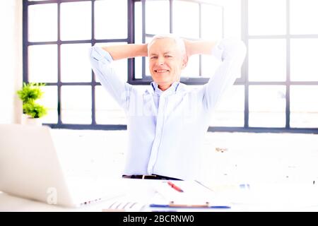 Schuss eines lächelnden zufriedenen Mannes, der während der Arbeit am Laptop zuhause im Stuhl ruht. Heimbüro. Stockfoto