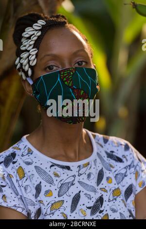 Eine kenianische Frau, die eine hausgemachte Maske trägt, aus traditionellem Kanga-Stoff zum Schutz vor einer Kovid-19-Pandemie. Chirurgische Masken befinden sich in kurzer Sup Stockfoto