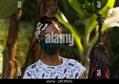 Eine kenianische Frau, die eine hausgemachte Maske trägt, aus traditionellem Kanga-Stoff zum Schutz vor einer Kovid-19-Pandemie. Chirurgische Masken befinden sich in kurzer Sup Stockfoto