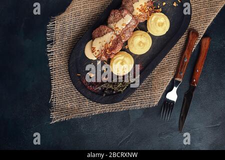 Gegrillte Schweinekoteletts mit Kartoffelpüree. Auf einem dunklen Holzhintergrund, rustikaler Stil. Food-Foto. Stockfoto