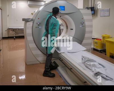 Computertomographie-Gerät (CT) in der Radiologieabteilung mit Radiologietechniker tragen persönliche Schutzausrüstung (PSA) Desinfektion Stockfoto