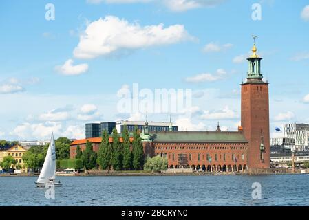 Stockholm, Schweden - 2. August 2019: Schöne Sommeransicht des Rathauses in der Altstadt (Gamla Stan) und eine Yacht auf dem Wasser Stockfoto