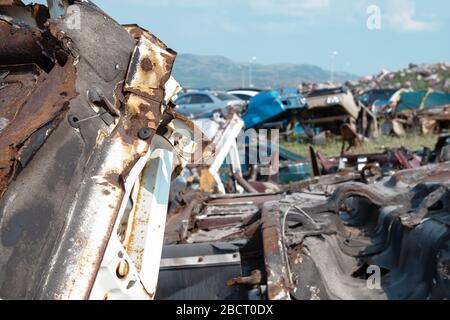 Deponierung alter verrostter Autos auf dem Junkyard, variierte Farbwagen verschwommen im Hintergrund Stockfoto