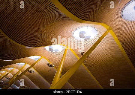 Moderne Decke des internationalen Flughafens Madrid Barajas. Decke mit Holzbohlen und gelben Säulen im Wellenstil. Internationales Terminal Stockfoto