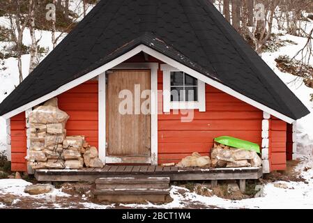 Rotes Holz-Barbcue-Haus mit kleinem Fenster in weißem Rahmen, typisch skandinavische Hausarchitektur Stockfoto