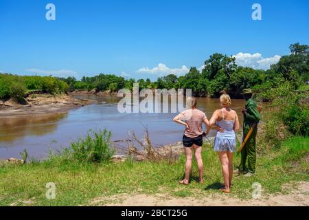 Touristen, mit einem Park Ranger, Blick auf Nilpferde und Krokodile in der Mara River, Mara Triangle, Masai Mara National Reserve, Kenia, Ostafrika Stockfoto