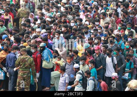 Mawa, Dhaka, Bangladesch. April 2020. Tausende von wiederverarbeiteten Kleidungsarbeitern aus dem ganzen Land waren in den letzten Tagen entweder gegangen oder nutzten alternative Transpirationsmethoden, um die Hauptstadt Dhaka zu erreichen, da die Eigentümer beschlossen hatten, die Fabriken inmitten einer staatlich erzwungenen weichen Abschaltung zu eröffnen, um zu verhindern, dass sich das neue Coronavirus weiter ausbreitet. Aber nach harschen Kritikpunkten war die BGMEA gezwungen, die Fabriken bis zum 11. April geschlossen zu halten. Den Arbeitern wurde gesagt, sie sollten nach Hause gehen, als sie am Sonntagmorgen in die Fabriken gingen, um sich der Arbeit anzuschließen. Diese photoss von Menschen, die in ihr Dorf hom zurückkehren Stockfoto