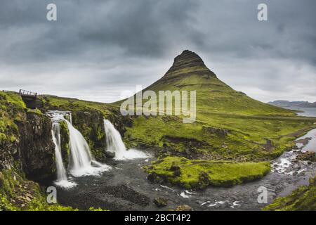 Kirkjufellsfoss Wasserfall und Kirkjufell Berg dahinter. An sehr bewölkten und regnerischen Tagen in Island. Stockfoto