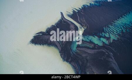 Blaues Flussdelta, das in den Teich fließt. Draufsicht. Luftaufnahmen. Interessante Textur. Stockfoto