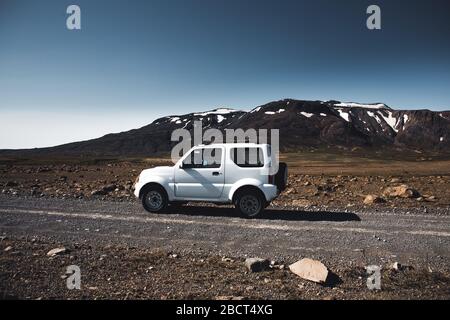 4x4 Jeep Suzuki Jimny ist auf der Straße in der hellen Sonne Blendung und Reflexionen. Ein kleiner SUV auf den Straßen Islands irgendwo in den Bergen. Stockfoto