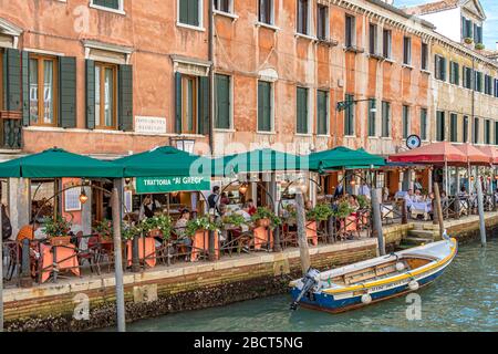 Leute, die außerhalb der Trattoria da Giorgio Al Greci essen, ein italienisches Restaurant am Kanal auf Fondamenta S. Lorenzo, Venedig, Italien Stockfoto