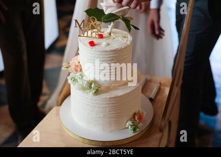 Mehrstufiger weißer Hochzeitstorte mit Figuren der Brautpaar. Nahaufnahme Stockfoto