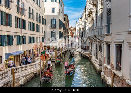 Menschen, die über eine Kanalbrücke mit Gondeln schlendern, nehmen Touristen mit auf Gondelfahrten entlang des rio del Palazzocanal in der Nähe des Dogenpalastes in Venedig Stockfoto