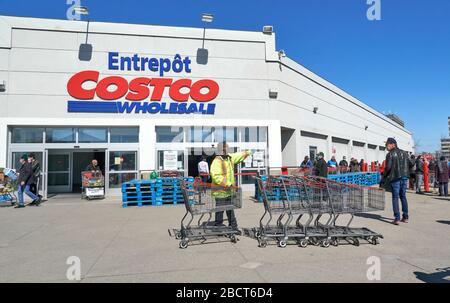 Montreal, Kanada - 4. April. 2020: Menschen mit Masken in einer Linie, um Costco Großhandel zu betreten. Viele Geschäfte führten soziale Distanzierungen durch, die zu Linien führten Stockfoto