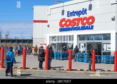 Montreal, Kanada - 4. April. 2020: Menschen mit Masken in einer Linie, um Costco Großhandel zu betreten. Viele Geschäfte führten soziale Distanzierungen durch, die zu Linien führten Stockfoto