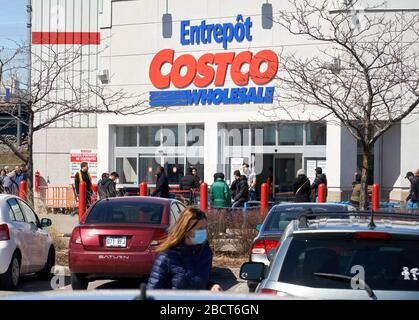 Montreal, Kanada - 4. April. 2020: Menschen mit Masken in einer Linie, um Costco Großhandel zu betreten. Viele Geschäfte führten soziale Distanzierungen durch, die zu Linien führten Stockfoto