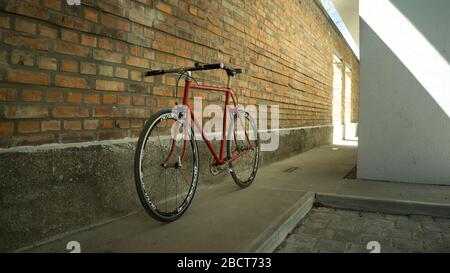 Retro-gestyltes, rotes, singlespeed, festes Zahnrad, isoliert an einer Ziegelwand Stockfoto