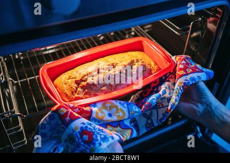 Eine Frau legt einen Kuchen in den Ofen Stockfoto