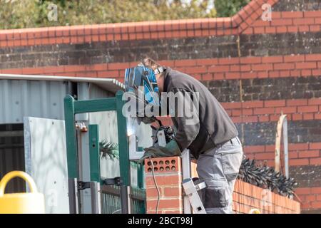 Bristol-April-2020-England, eine Nahaufnahme eines Mannes, der eine Metallleitung an das Hauptsicherheitstor schweißt Stockfoto