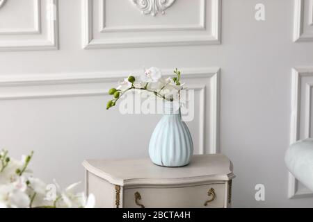 Weiße Orchideenblüten in Vase auf dem Tisch. Vintage-Vase mit Orchidee zu Hause auf der Kommode Stockfoto