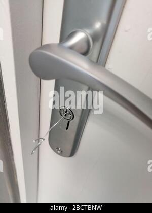 Kleiner Metalldraht in das Schlüsselloch der Tür zum Entriegeln von Türen ohne Schlüssel eingeführt Stockfoto