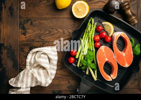 Unbehaart mit Lachssteaks und Gemüse auf einer Metallgrillpfanne. Draufsicht mit Kopierbereich für Rezept, Text oder Design. Konzept des Kochens gesunder Lebensmittel Stockfoto