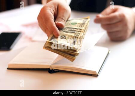 Hände des Geschäftsmannes mit Papiergeld. Heimbüro. Das Gehalt für die Arbeiter wird gezählt Stockfoto