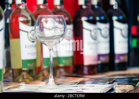 Sumy, Ukraine - 25. August 2019. Das zweite Weinfest in Sumy. Ein leeres Weinglas steht auf einem Tisch inmitten von Flaschen Rot- und Weißwein. Weinprobe Stockfoto