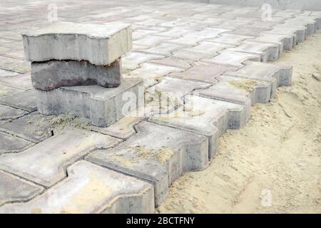 Straßenarbeiten zu ersetzen Pflasterplatten. Reparatur des Bürgersteiges, Pflasterplatten. Verlegung neuer Straßenfliesen in den Sand Stockfoto
