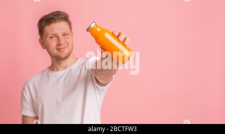 Junger Mann, der eine Glasflasche mit Vitamingetränk hält, um die Immunität zu erhöhen Stockfoto