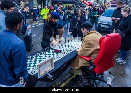 London Street Chess - ein Schachspieler spielt bis zu 4 gleichzeitige Spiele mit Touristen und Passanten auf dem beliebten Londoner Brick Lane Sunday Market Stockfoto