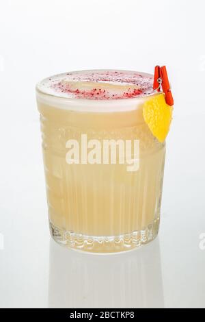 Nahaufnahme einer Hand, die ein Glas Whisky Sour Cocktail auf weißem Hintergrund mit Kopierraum hält. Stockfoto