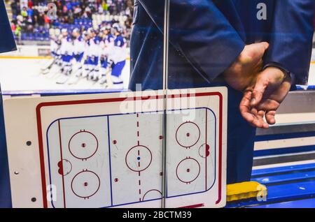 Trainieren Sie auf der Eishockeybank mit taktischem Brett, um den Spieler nach dem Eishockeyspiel zu betrachten. Stockfoto