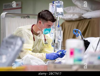 Das U.S. Navy Hospital Corpsman, 2. Klasse Trevor Aguiar, behandelt einen Patienten an Bord des Hospitalschiffs USNS Mercy, das zur Unterstützung der COVID-19, Coronavirus Pandemie, 4. April 2020 in Los Angeles, Kalifornien, eingesetzt wird. Stockfoto