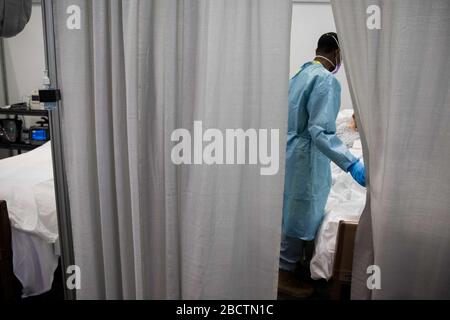 Ein US-Arzt prüft einen Patienten auf der Intensivstation auf COVID-19, eine pandemische Linderung des Coronavirus im Jacob Javits Center am 4. April 2020 in New York City, New York. Stockfoto