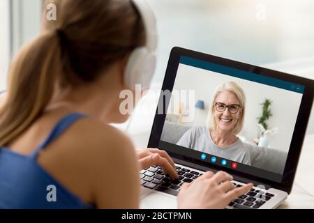 Blick über die Schulter Erwachsene Tochter Gespräche von Videokall mit Mutter Stockfoto