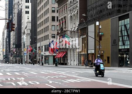 New York City, USA. April 2020. Eine Frau fährt einen Rent-A-Roller eine leere Sekte der 5th Avenue hinunter, da New Yorker zu Hause bleiben sollen und nicht-essentielle Geschäfte aufgrund der Coronavirus Pandemie, New York, NY, 5. April 2020 in der Nähe bleiben. New York Reg. Andrew Cuomo gab den ersten Rückgang der Zahl der Todesfälle aufgrund der COVID-19-Infektion im Staat New York bekannt, ohne den Grund dafür zu geben. (Anthony Behar/Sipa USA) Credit: SIPA USA/Alamy Live News Stockfoto