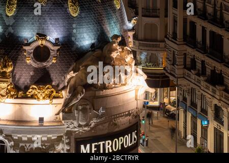 MADRID, SPANIEN - 13. APRIL 2019: Detail der Metropolis-Baukuppel, deren Statuen einen Finger auf die Passanten zu zeigen scheinen, die auf Madrids Seite spazieren Stockfoto