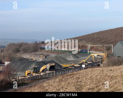 Shap Summit an der Westküste Mainline. Ein Virgin trainiert pendolino, der als DRS-Güterzug vorbeifährt, wird in den Querstein-Abstellgleisen mit Eisenbahnballast beladen Stockfoto