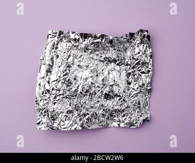 Zerknitterte Folie verwendete Süßigkeiten-Wrapper auf einem lilafarbenen Hintergrund, Draufsicht Stockfoto
