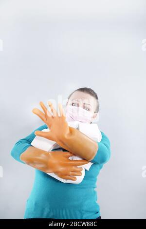 Eine Frau trägt eine Gesichtsmaske zum Schutz vor dem Corona-Virus und hat sich im Falle einer Quarantäne auf ihrem toilettenpapierstich aufgefüllt. FEM im mittleren Alter Stockfoto