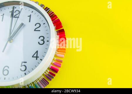Eine Reihe von kosmetischen Werkzeugen für Maniküre und Pediküre auf blauem Hintergrund. Die Uhr und die Farbpalette für Manikureons auf Spitzen stehen unter der Uhr Stockfoto