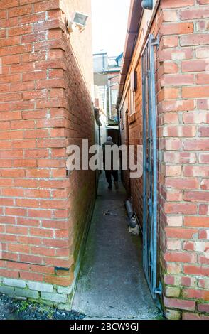 Person, die entlang einer engen Gasse zwischen Geschäften führt vom Marktplatz zum Parkplatz in Poulton le Fylde Lancashire England Großbritannien. Stockfoto