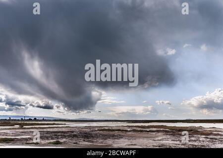 Dunkle Sturmwolke, die Regen in der Bucht von South San Francisco bringt; Tidaleiche und Marschland unter den Wolken sichtbar; Don Edwards National Wildlife Refuge, Stockfoto